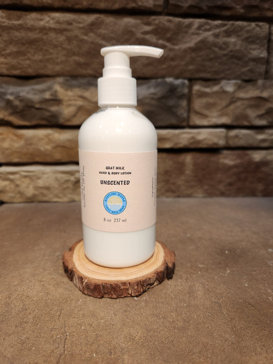 Unscented bottle of goat milk hand and body lotion sitting on a wood display with a stone background.