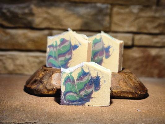 Colorful soap bars with a natural pattern on a wooden block against a stone wall background