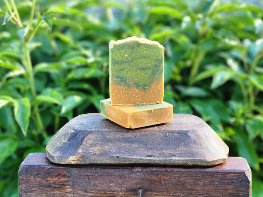 Two green and brown soap bars on a wooden block with a natural background