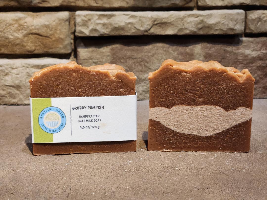Two bars of soap with a label in front of a stone wall.