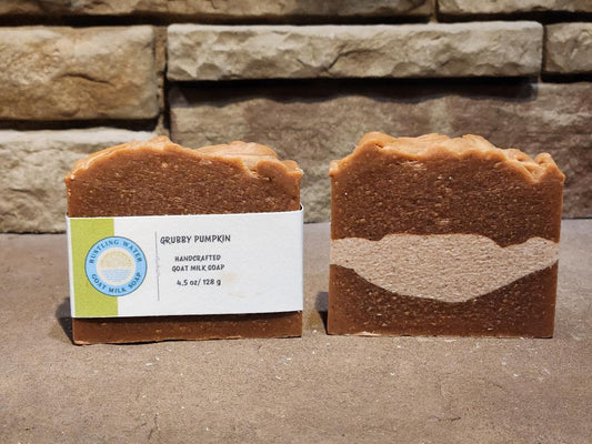 Two bars of soap with a label in front of a stone wall.