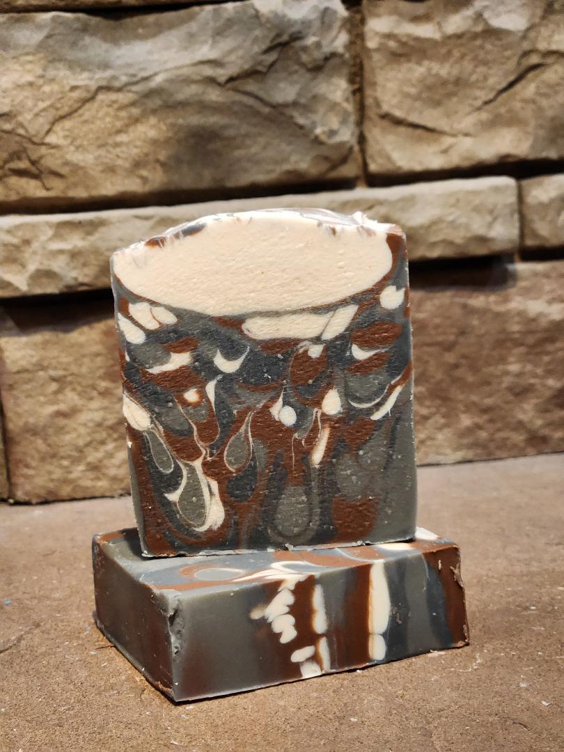 Marbled soap bar with brown, beige, and white colors on a stone surface.
