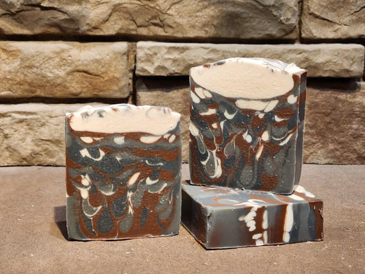 Marble-patterned soap bars on a stone surface with a stone wall background