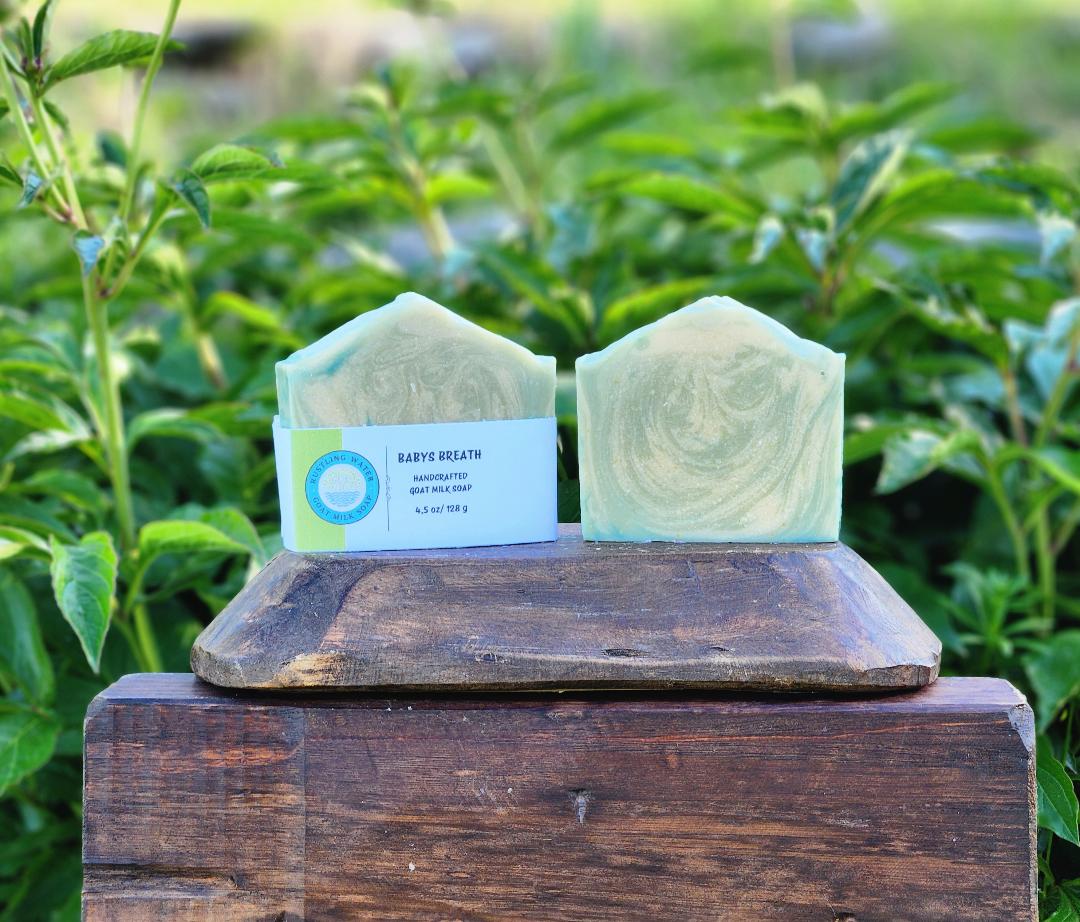 Two green soap bars on a wooden block with a natural background