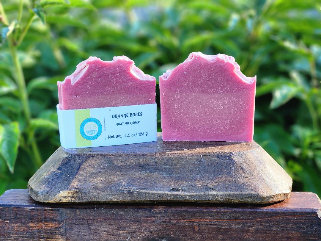 Two pink soap bars on a wooden stand with a green leafy background