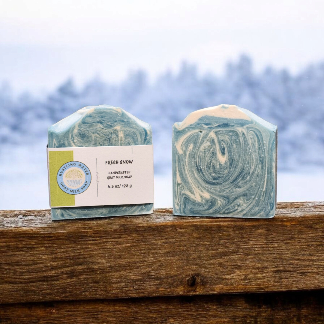 Two swirled soap bars on a wooden surface with a blurred natural background