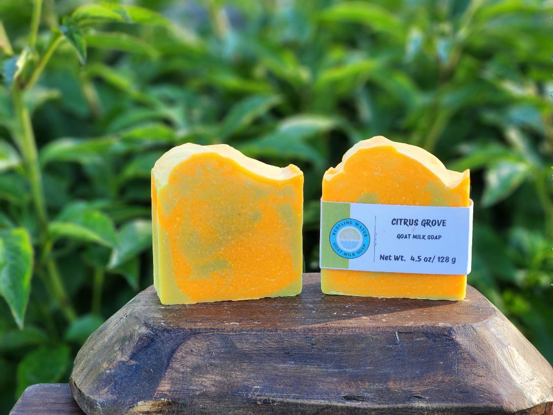 Two yellow soap bars on a wooden block with a green leafy background