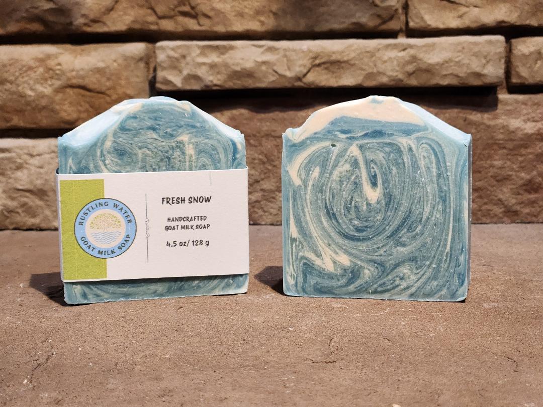 Two swirled soap bars with a label on a stone surface