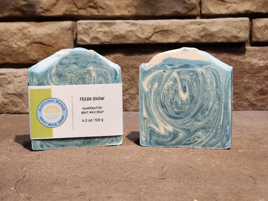 Two swirled soap bars with a label on a stone surface